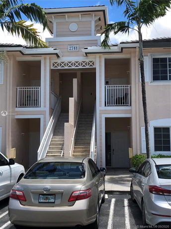 Front view of a two-story residential building with an exterior staircase and balconies.