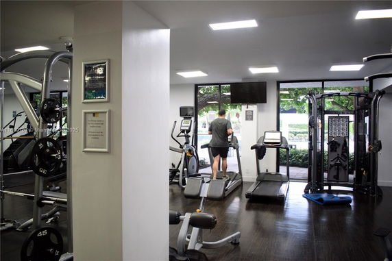 Indoor gym area with exercise equipment and a person using a treadmill.