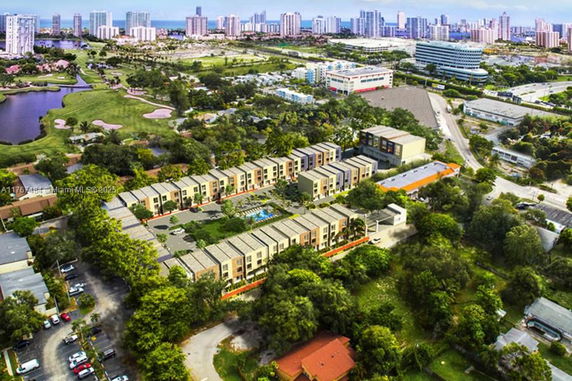 Wide angle view of a residential area surrounded by greenery and cityscape.