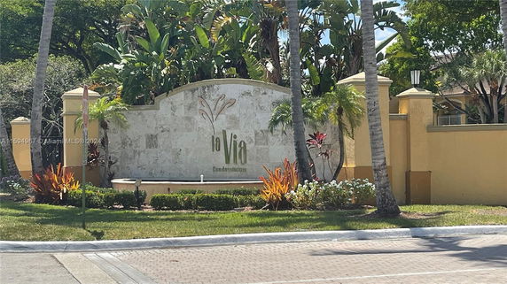 Entrance view of La Via Condominium with a decorative wall and landscaping.