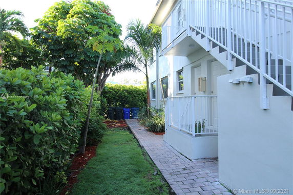 Side view of a multi-story building with external stairs and surrounding greenery.
