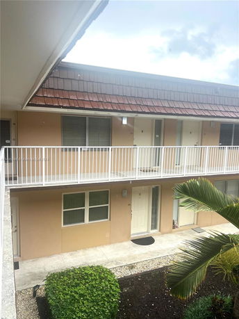View of an apartment complex with balconies and a small garden area.