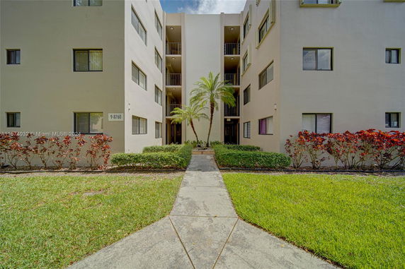 Front view of a multi-story building with a walkway and landscaping.