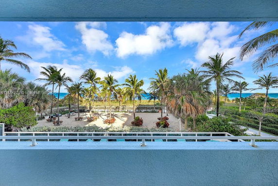 View of a landscaped area with palm trees and ocean in the background.