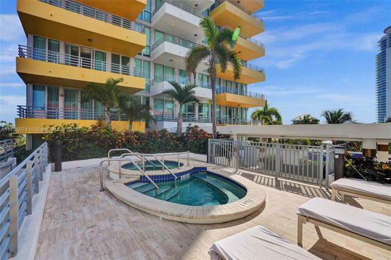 Outdoor swimming pool area with lounge chairs and a view of a multi-story building.