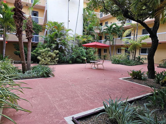 Courtyard area with tables, chairs, and surrounding green foliage.