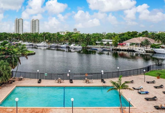 View of a pool area overlooking a marina with boats and a distant view of buildings.