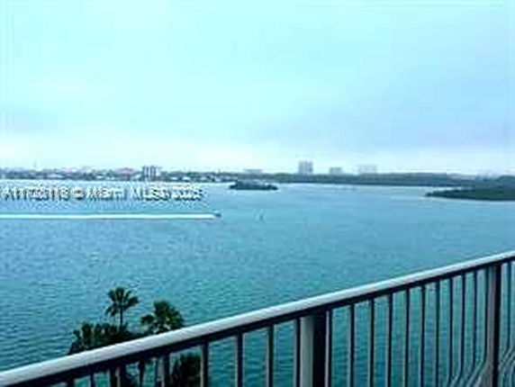 Panoramic view from a balcony overlooking a large body of water and distant skyline.