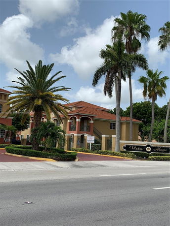 Front view of a multi-story building with arched entryways and a red-tiled roof.