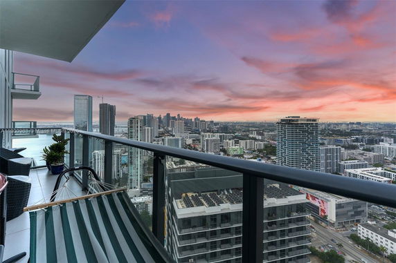 Panoramic view from a high-rise balcony overlooking a city skyline at sunset.
