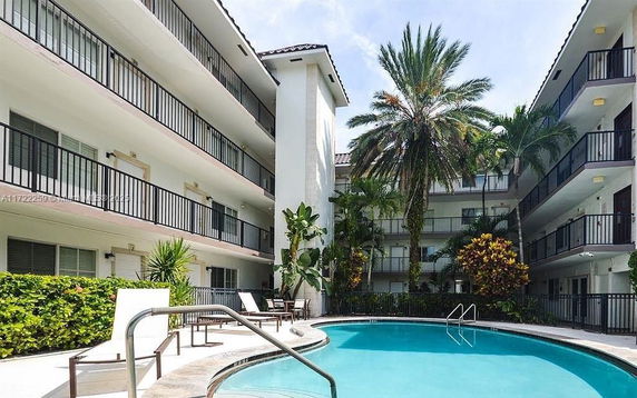Outdoor area with a swimming pool surrounded by a multi-story residential building.