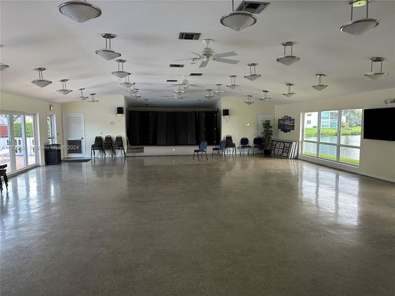 Spacious indoor area with chairs, stage, and large windows overlooking outdoors.