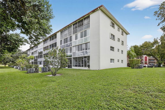 Side view of a multi-story residential building with enclosed balconies.