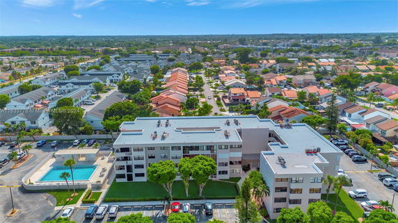 Aerial view of a multi-story building with a flat roof in a suburban area.