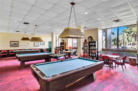 Recreation room with pool tables, seating, and large windows.