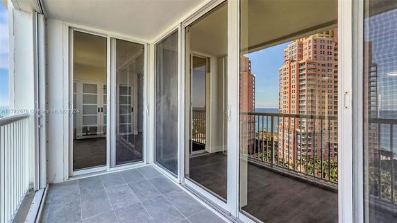 Balcony view with tall buildings and the ocean in the background.