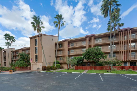 Front view of a multi-story residential building with balconies and palm trees.