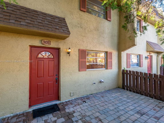 Front view of a two-story townhouse with red door and beige exterior walls.