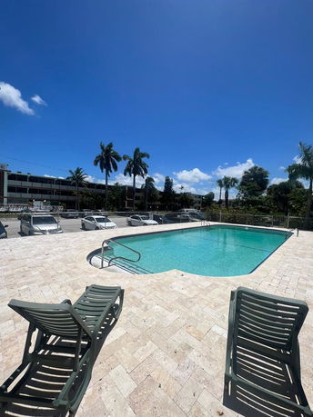 Outdoor swimming pool area with lounge chairs and surrounding buildings.