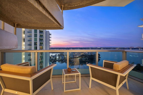 Balcony view of high-rise buildings and waterfront during sunset.