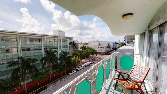 View from a balcony showing nearby buildings and streets with palm trees.