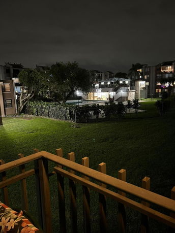 Nighttime view of residential buildings and grass area from a balcony.