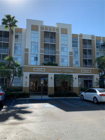 Front view of a multi-story residential building with a parking area in front.