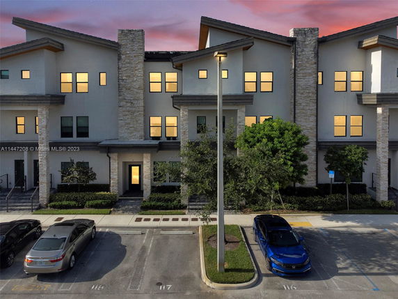 Front view of a multi-story building with stone accents and a parking area.