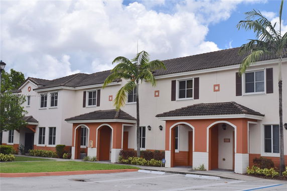 Front view of a two-story building with a brown tiled roof and arched entryways.
