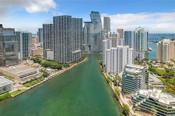 Panoramic view of a city's waterfront skyline with high-rise buildings along a river.