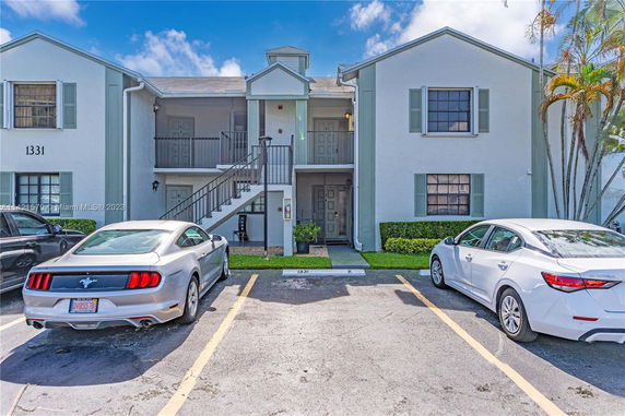 Front view of a two-story residential building with parking area in front.