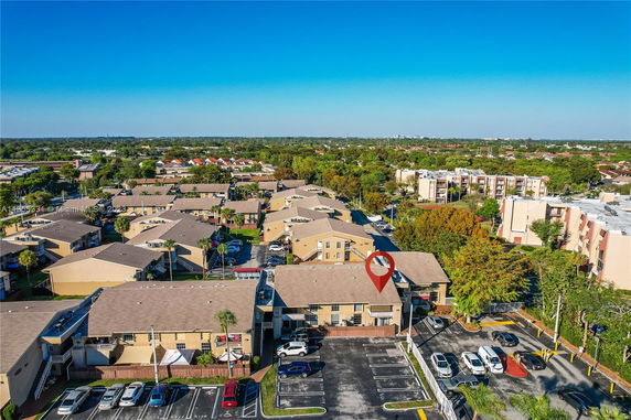 Aerial view showing multiple residential buildings with parking spaces and surrounding greenery.