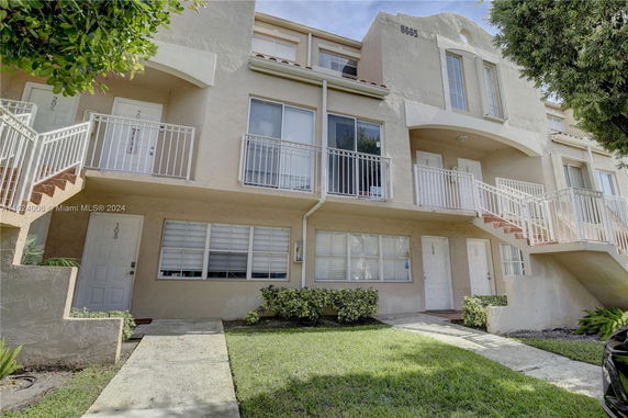 Front view of a multi-story residential building with balconies and exterior staircases.