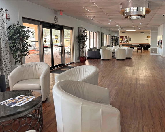 Interior view of a clubhouse with seating area and wooden floor.
