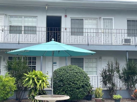 Front view of a two-story building with a balcony and plants.