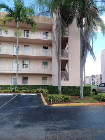 Parking area in front of a multi-story residential building with balconies.