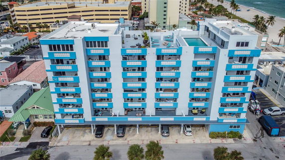 Front view of a multi-story building with blue balconies and a garage area on the ground floor.