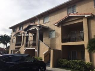 Front view of a multi-story residential building with balconies and tiled roof.