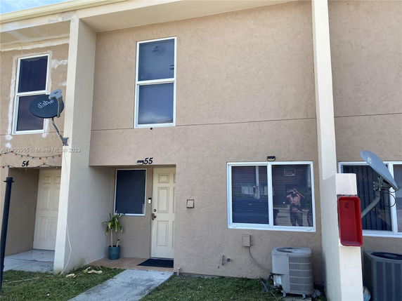 Front view of a two-story building with beige stucco exterior and a numbered door.