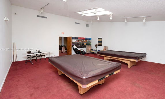 Indoor room with pool tables and bookshelves.