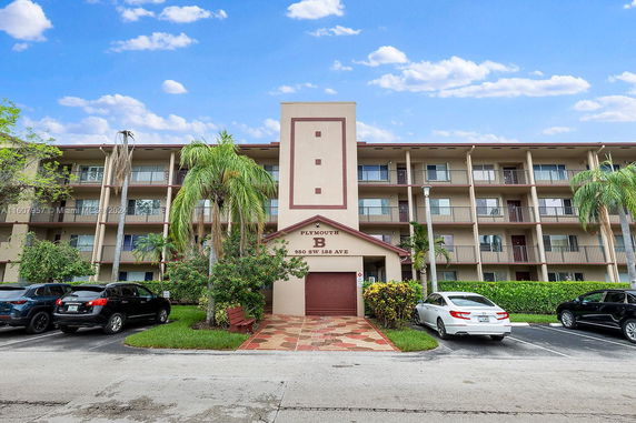 Front view of a multi-story residential building with balconies and parking area.