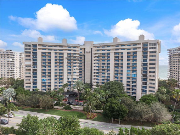 Front view of a multi-story condominium building with balconies and large windows.