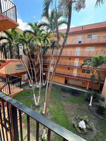 View of a multi-story building with a courtyard and palm trees.
