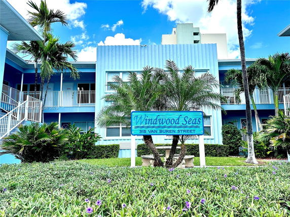 Front view of a two-story building with blue exterior and balcony railings.