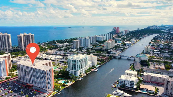 Aerial view of a coastal city with multiple high-rise buildings near a waterway and ocean.