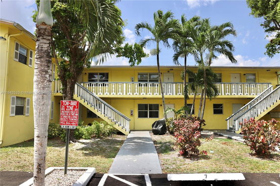 Front view of a two-story yellow apartment building with external staircases.
