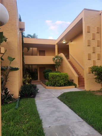 Front view of a multi-story building with stairs and landscaping.