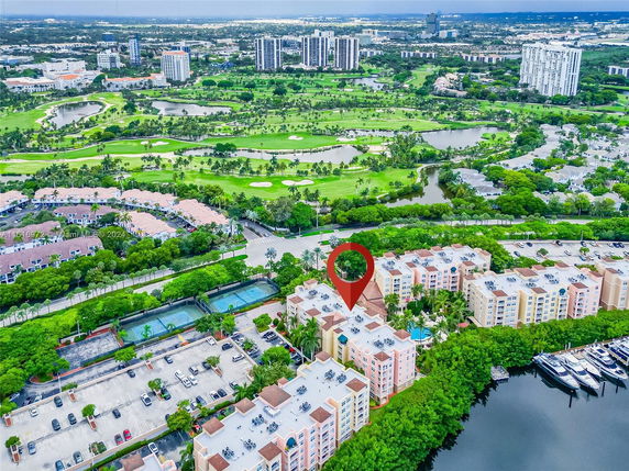 Aerial view showing a complex of residential buildings and a vast landscape including golf courses and waterways.