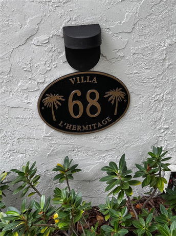 Exterior wall of a building with a villa number plaque and light fixture.