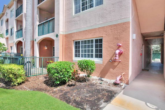 Front view of a multi-story apartment building with balconies and light-colored wall panels.